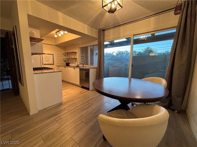 dining space featuring light wood finished floors and a textured ceiling