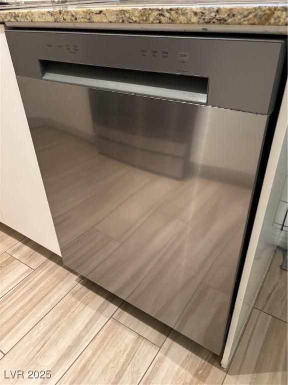 interior details featuring stainless steel dishwasher, light countertops, and light wood-type flooring