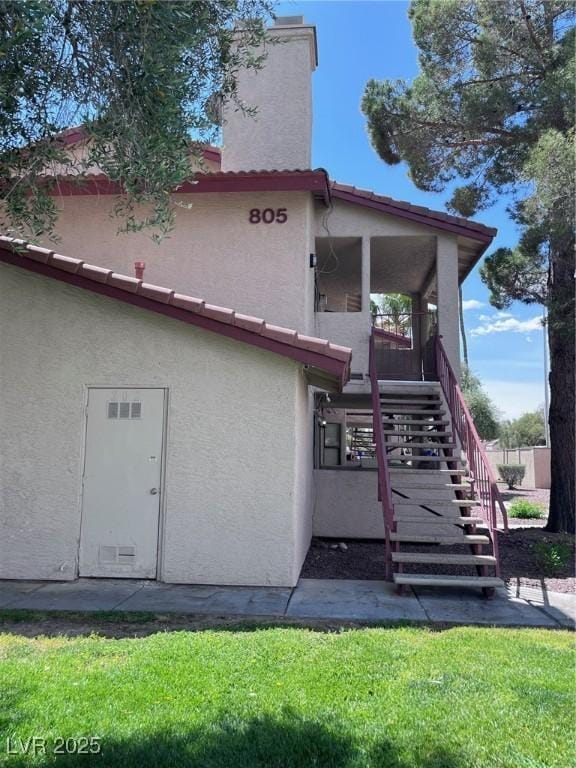 805 Rock Springs Dr Unit 101, Las Vegas, NV 89128 - exterior space featuring stucco siding, stairway, a chimney, and a lawn