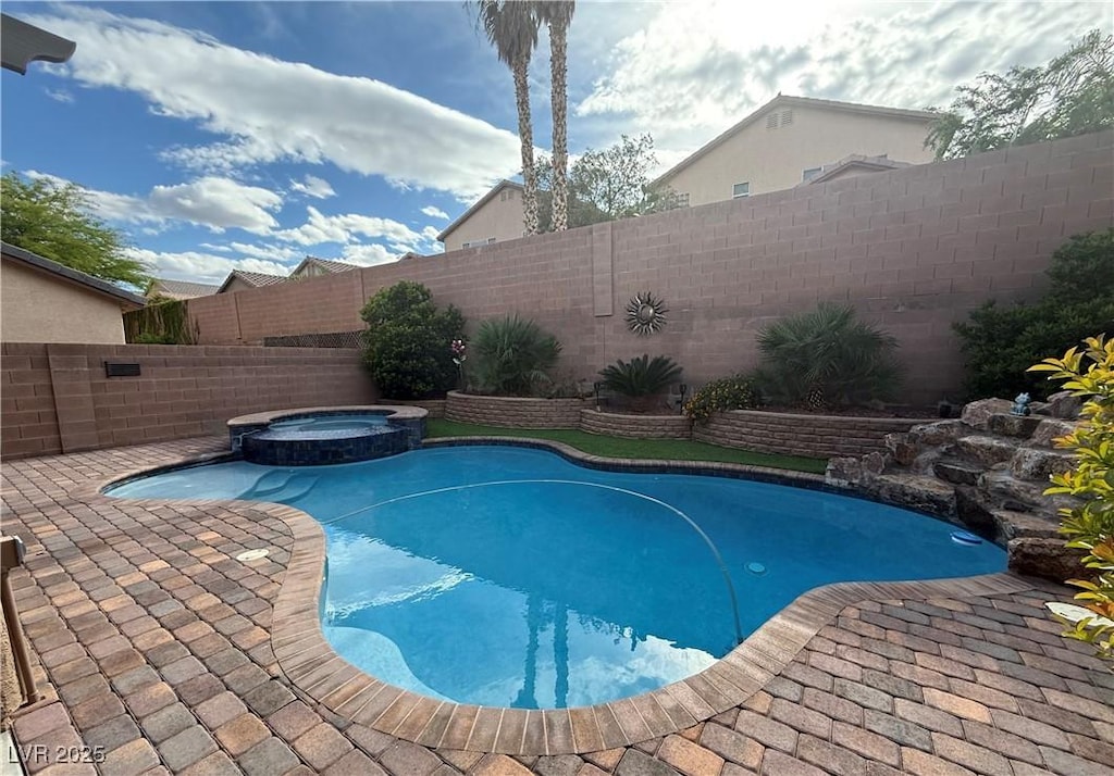 view of swimming pool featuring a fenced backyard, a pool with connected hot tub, and a patio area