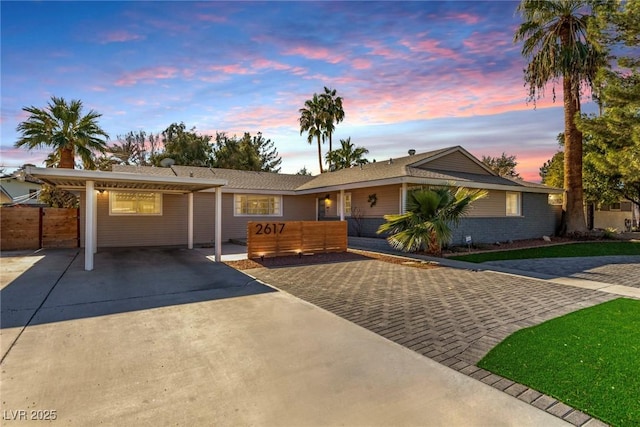 ranch-style home with concrete driveway and fence