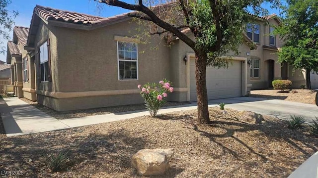 mediterranean / spanish home with a garage, stucco siding, a tile roof, and concrete driveway