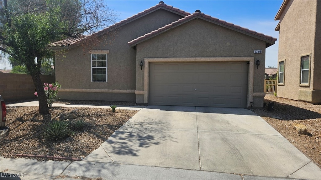 ranch-style house with fence, stucco siding, concrete driveway, an attached garage, and a tile roof