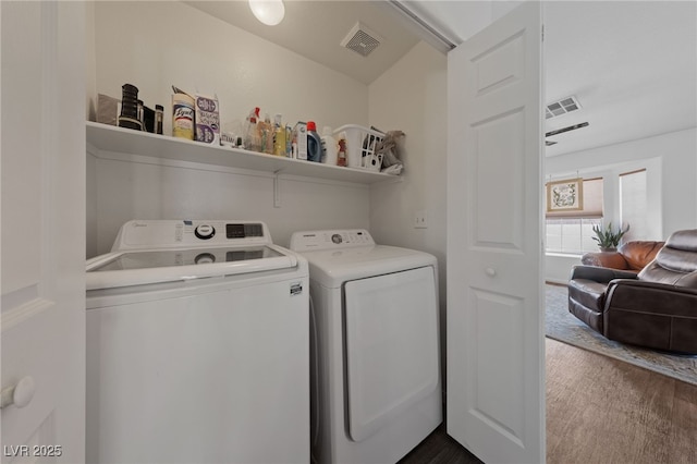 laundry area with washing machine and clothes dryer, laundry area, visible vents, and dark wood finished floors