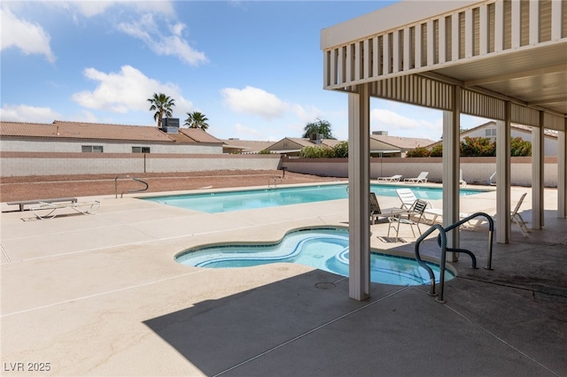 community pool with a community hot tub, a fenced backyard, and a patio area
