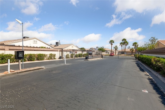 view of road with a gate, a gated entry, curbs, and a residential view