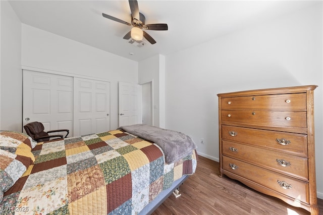bedroom featuring a closet, visible vents, wood finished floors, baseboards, and a ceiling fan