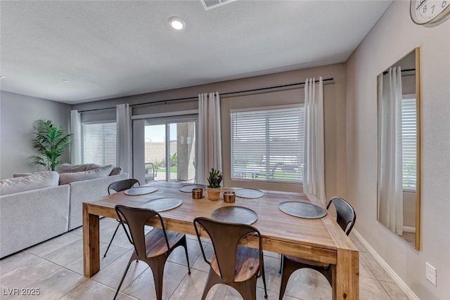 dining room with baseboards, a textured ceiling, and light tile patterned floors