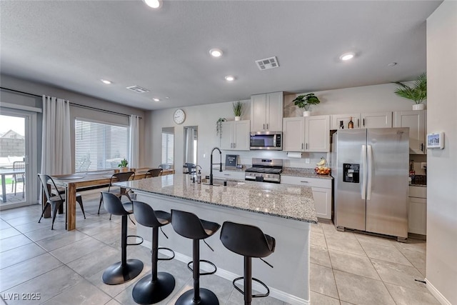 kitchen with a sink, a breakfast bar area, stainless steel appliances, and visible vents
