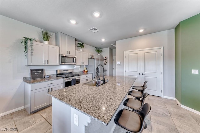 kitchen featuring baseboards, appliances with stainless steel finishes, a sink, and visible vents
