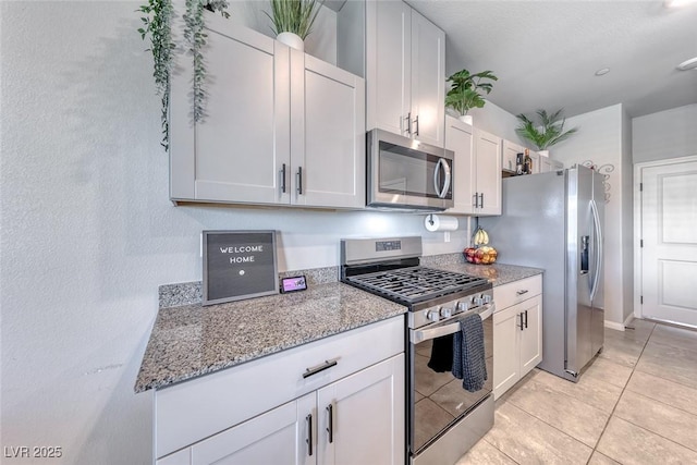 kitchen with light stone counters, white cabinets, stainless steel appliances, and light tile patterned flooring