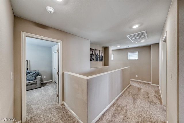 hall with carpet floors, baseboards, and visible vents