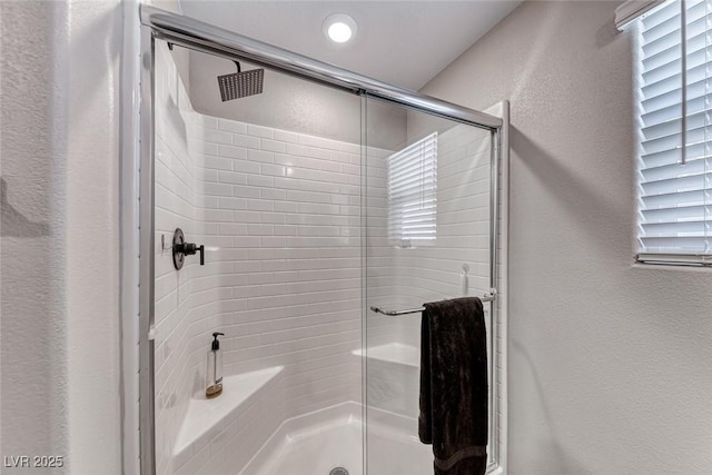 full bathroom with a textured wall and a shower stall