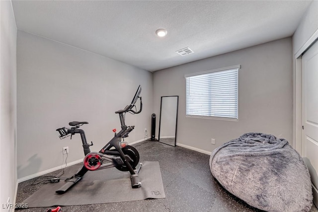 exercise area featuring visible vents, a textured ceiling, and baseboards