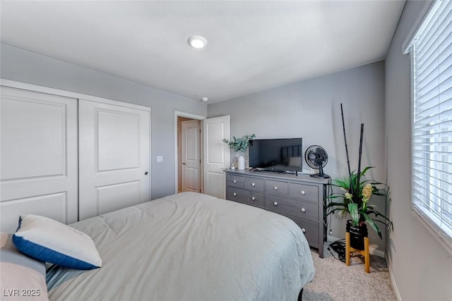 bedroom with baseboards, light carpet, and a closet