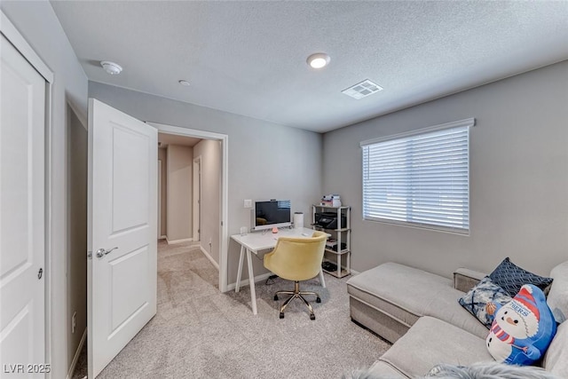 office area featuring a textured ceiling, light colored carpet, baseboards, and visible vents
