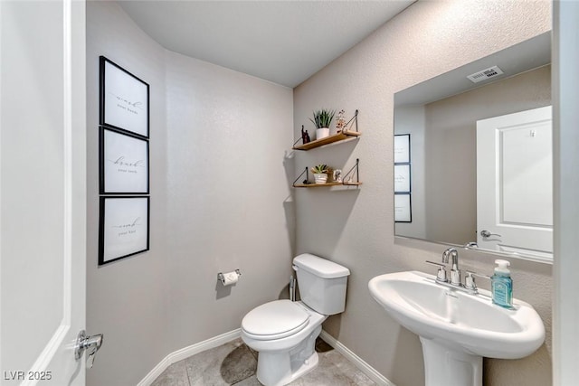 half bath with a sink, baseboards, toilet, and visible vents