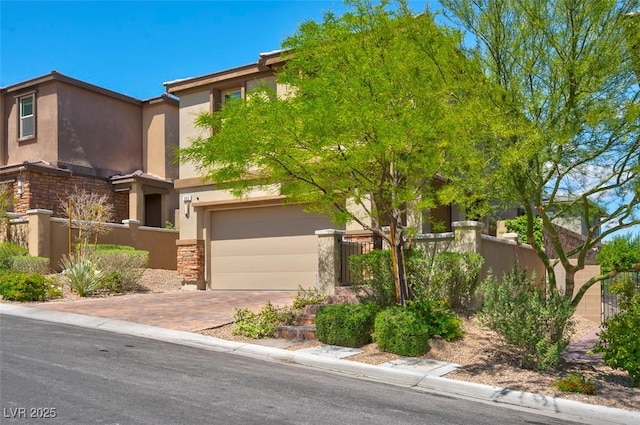 view of front of property featuring stucco siding, decorative driveway, fence, and stone siding
