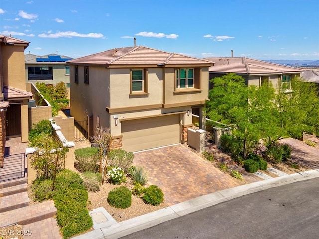 view of front of property featuring a gate, decorative driveway, fence, an attached garage, and stucco siding