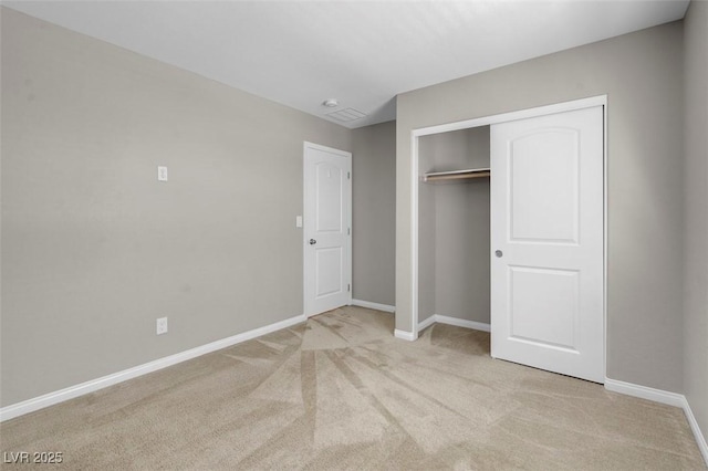 unfurnished bedroom with baseboards, light colored carpet, and a closet