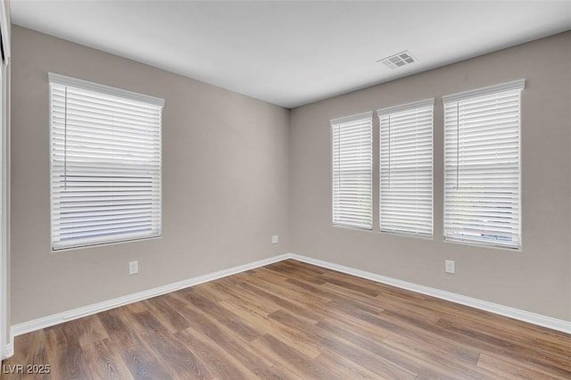 spare room with baseboards, wood finished floors, and visible vents