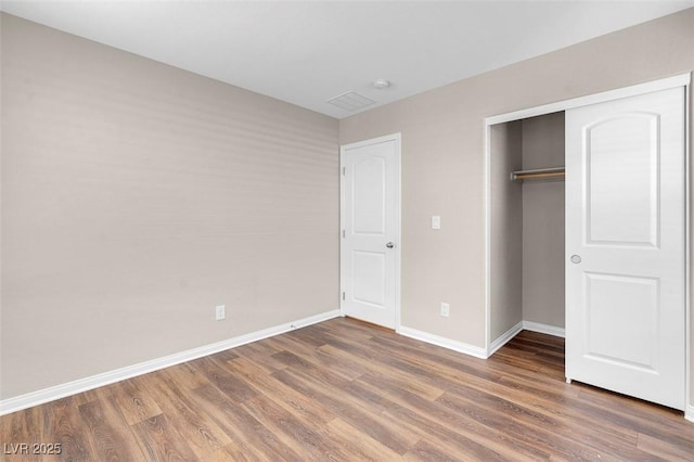 unfurnished bedroom with baseboards, a closet, and wood finished floors