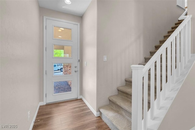 entrance foyer featuring stairway, baseboards, and wood finished floors