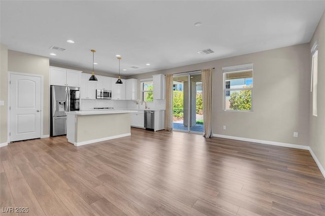 kitchen with visible vents, appliances with stainless steel finishes, a center island, light countertops, and open floor plan