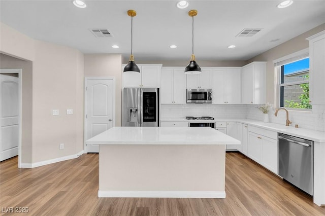kitchen featuring visible vents, a sink, a kitchen island, and stainless steel appliances