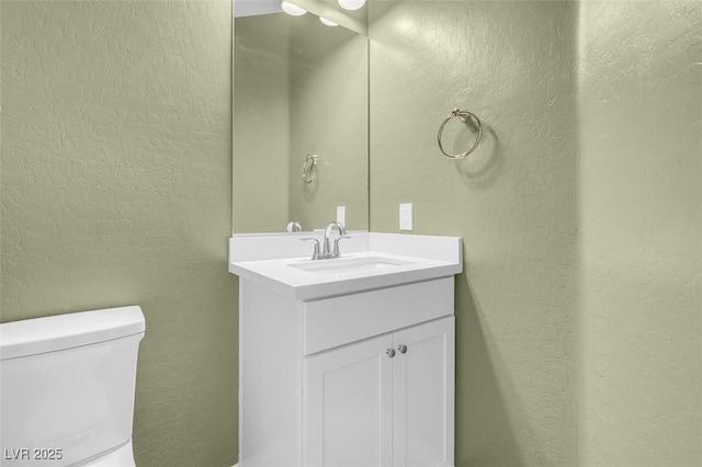 bathroom with vanity, a textured wall, and toilet
