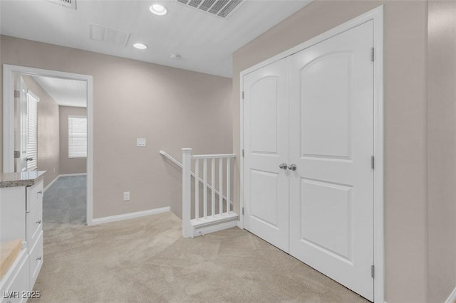 corridor featuring light colored carpet, baseboards, visible vents, and an upstairs landing