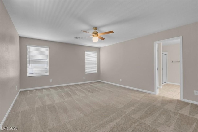 empty room with a ceiling fan, baseboards, plenty of natural light, and light carpet