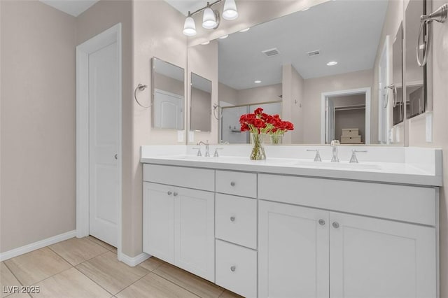 bathroom with double vanity, a shower stall, a sink, and a closet