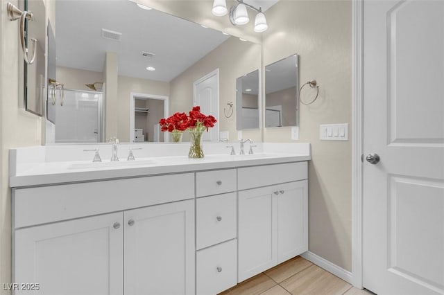 bathroom featuring visible vents, a sink, a shower with door, and double vanity