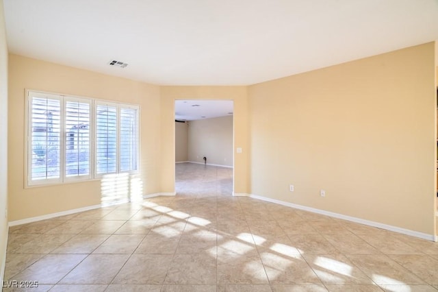 spare room featuring baseboards, light tile patterned flooring, and visible vents