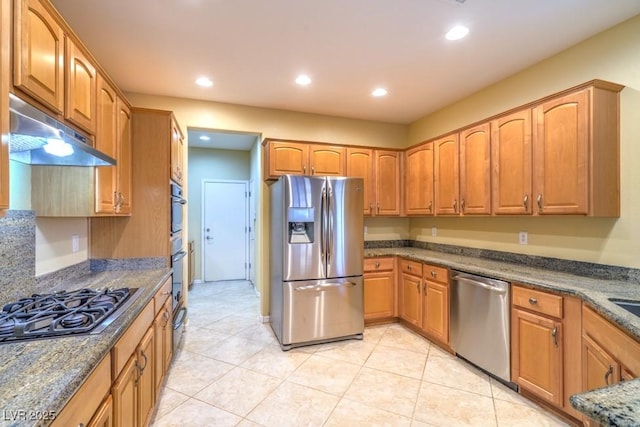 kitchen featuring appliances with stainless steel finishes, dark stone countertops, recessed lighting, light tile patterned floors, and under cabinet range hood