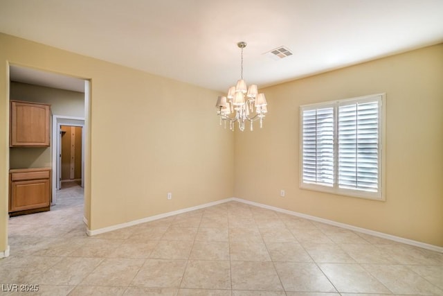 spare room with baseboards, a notable chandelier, and visible vents