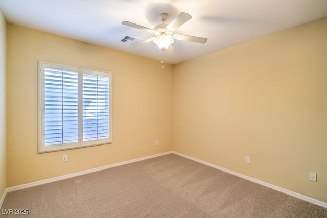 carpeted empty room featuring baseboards, ceiling fan, and visible vents