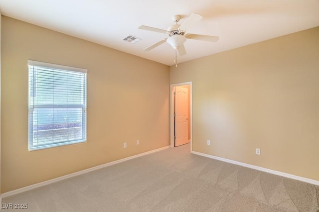 empty room with baseboards, ceiling fan, light carpet, and visible vents