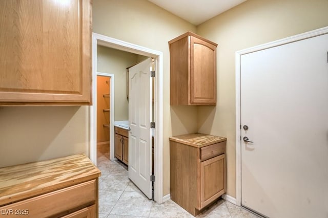 corridor featuring light tile patterned floors and baseboards