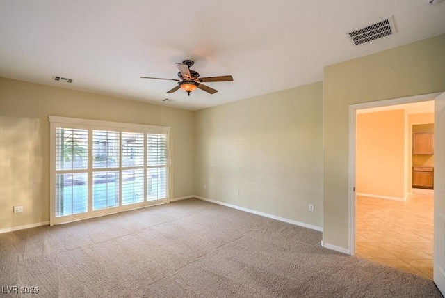 unfurnished room with baseboards, ceiling fan, light carpet, and visible vents