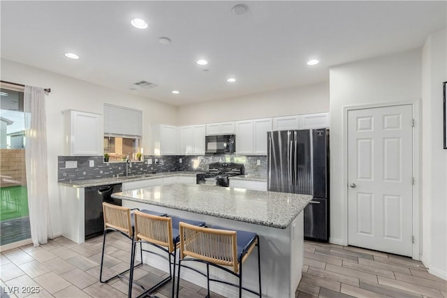 361 Andy Wheeler Dr, Henderson, NV 89011 - kitchen featuring a center island, visible vents, white cabinetry, black appliances, and tasteful backsplash