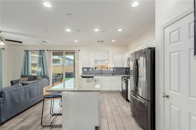 361 Andy Wheeler Dr, Henderson, NV 89011 - kitchen with a breakfast bar, freestanding refrigerator, black range with gas stovetop, open floor plan, and a kitchen island