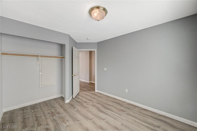 unfurnished bedroom featuring baseboards, wood finished floors, and a closet