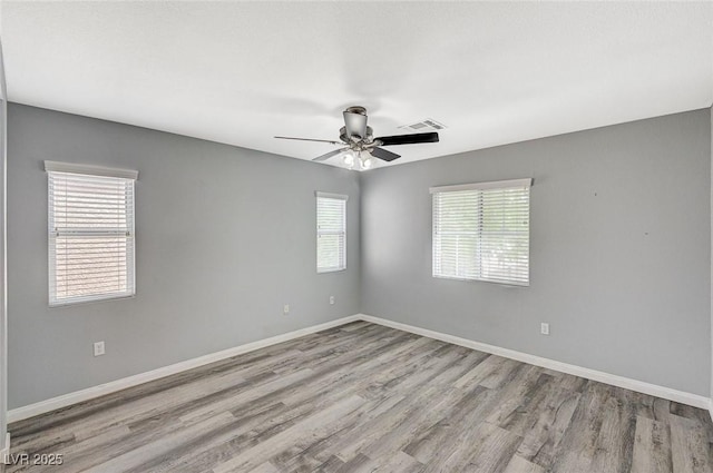 empty room with a ceiling fan, baseboards, visible vents, and wood finished floors