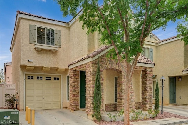 mediterranean / spanish house with a tiled roof, an attached garage, stone siding, and stucco siding