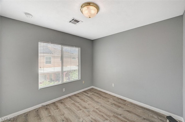 empty room featuring baseboards, wood finished floors, and visible vents