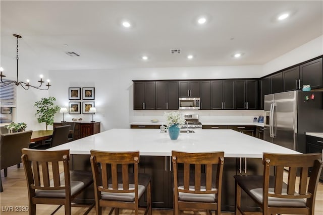 712 Webber Park St, Henderson, NV 89011 - kitchen with visible vents, appliances with stainless steel finishes, a large island with sink, light countertops, and an inviting chandelier