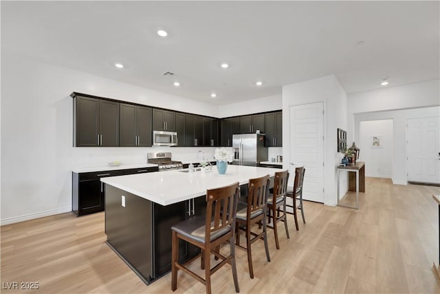 712 Webber Park St, Henderson, NV 89011 - kitchen with appliances with stainless steel finishes, light countertops, light wood-style flooring, a large island with sink, and a kitchen bar