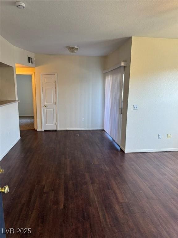 empty room with baseboards, visible vents, and wood finished floors